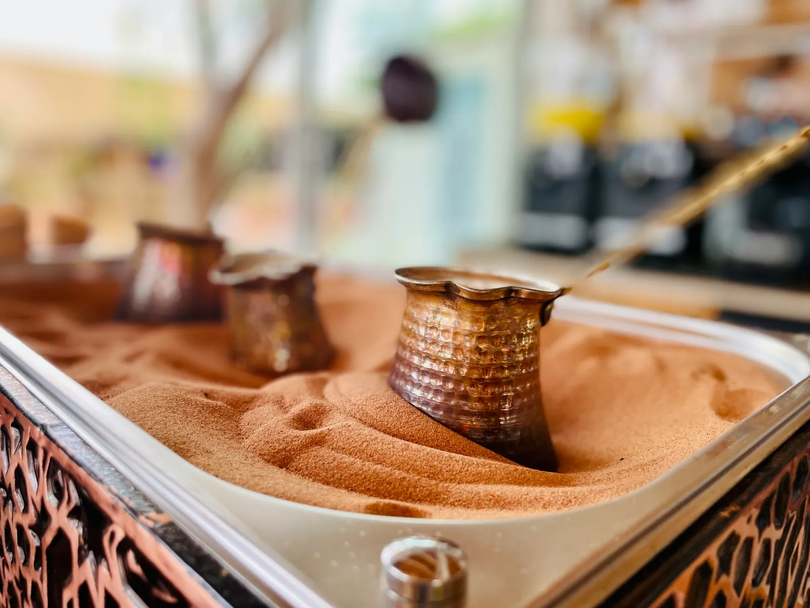 Copper coffee pots brewing in hot sand