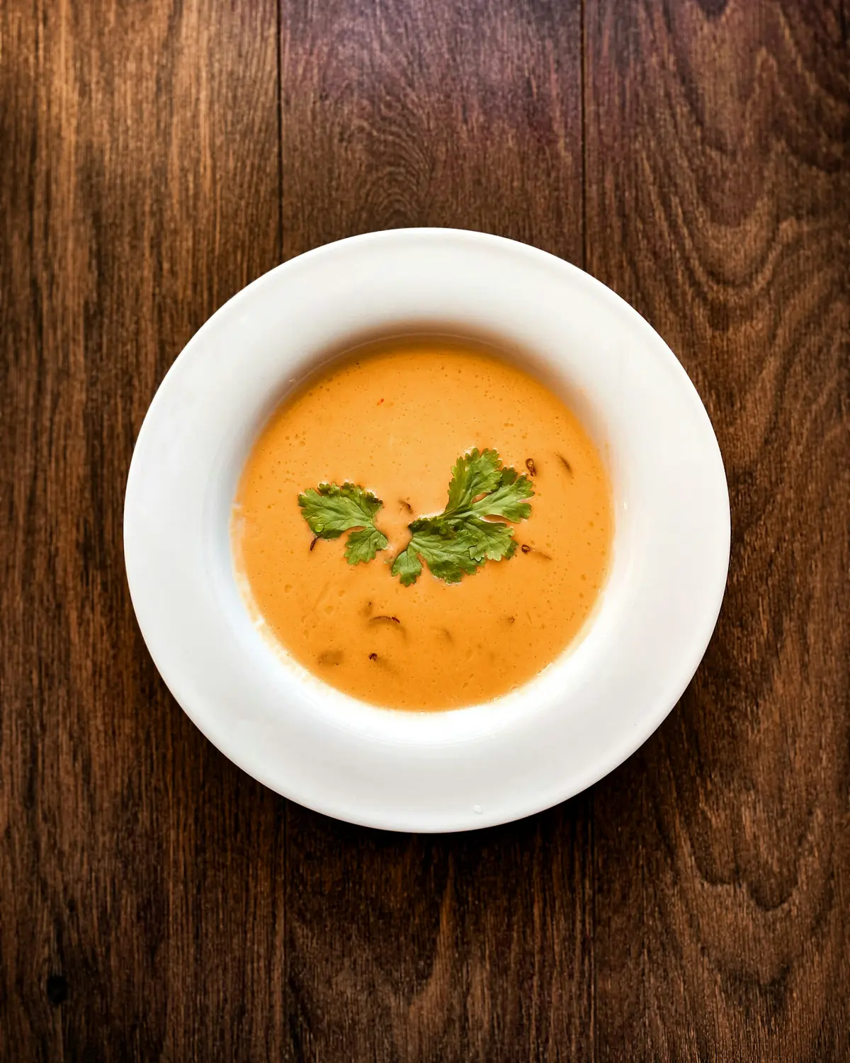 Orange lentil soup in a white bowl on a wooden table