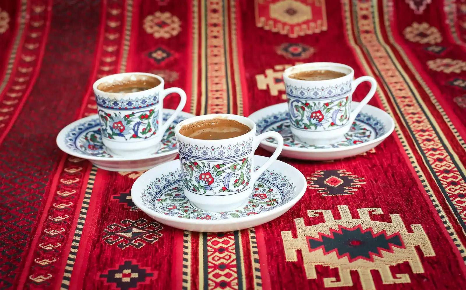 Turkish coffee in decorated cups on a red kilim